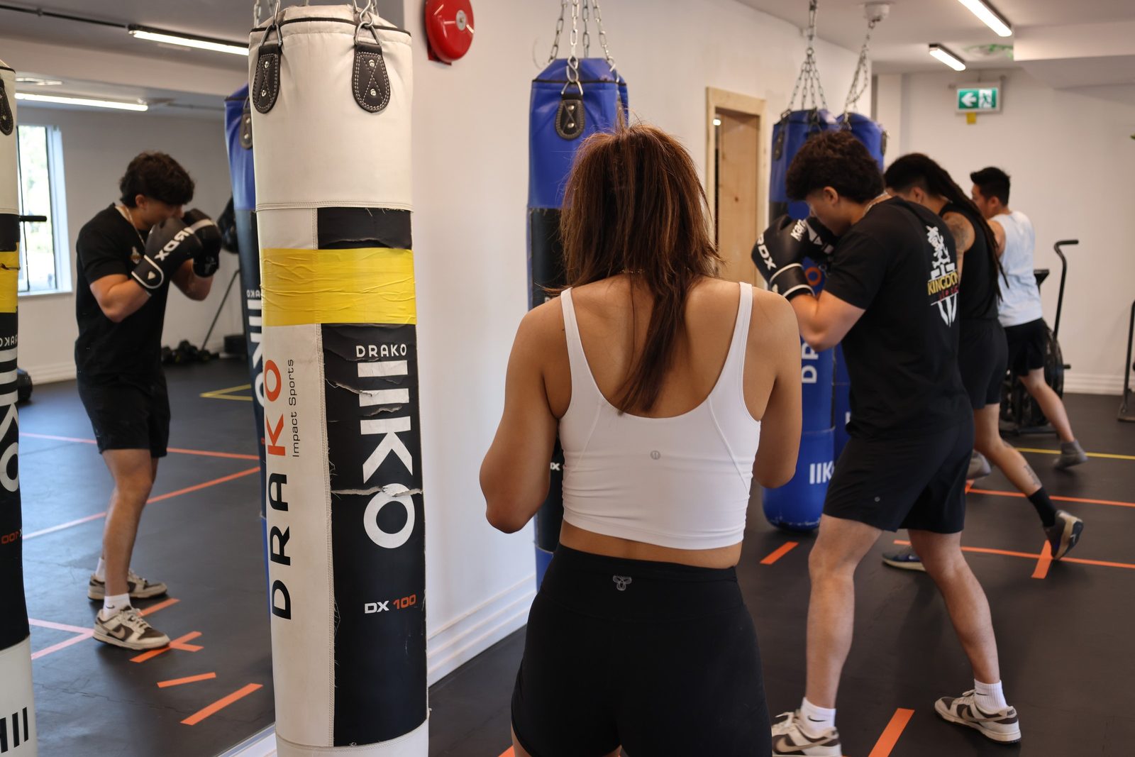 Adults working the heavy bags during a group boxing class at Kingdom Athletics
