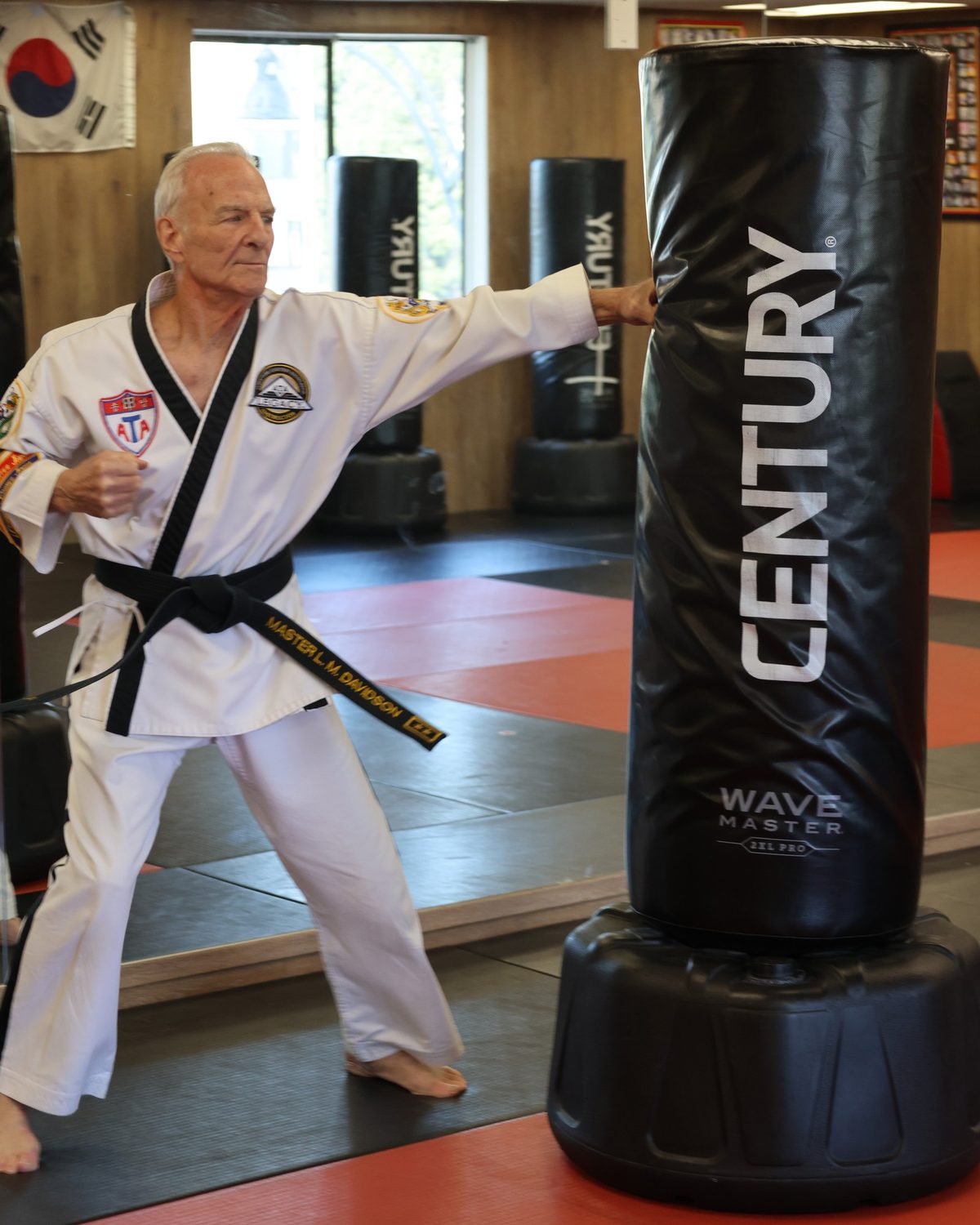 An older athlete throwing a controlled punch at a standing heavy bag, boxing for seniors white rock at Kingdom Athletics