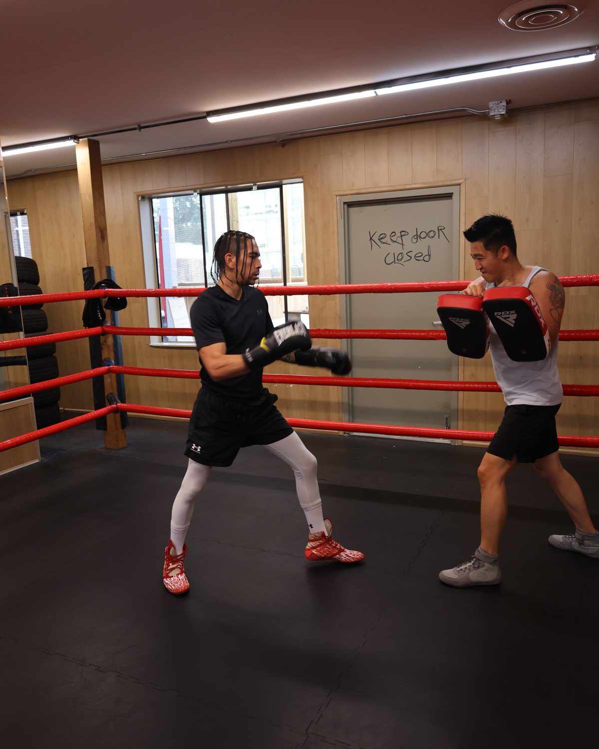 A coach holding pads for a member inside the ring, fitness classes south surrey at Kingdom Athletics