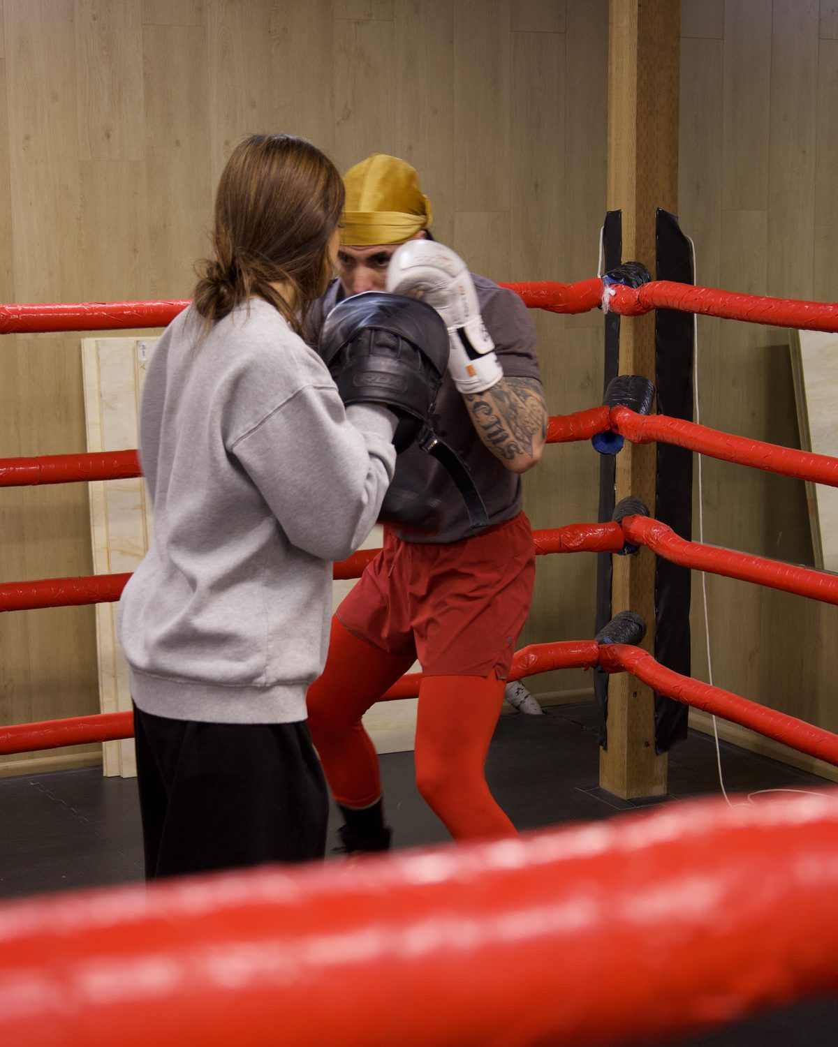 A coach holding pads for a beginner in the ring at Kingdom Athletics