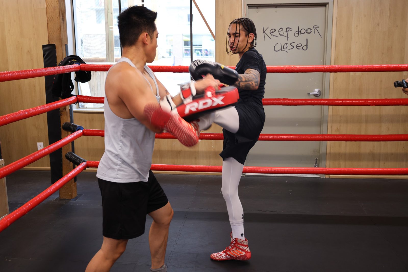 A knee strike into pads during kickboxing pad work at Kingdom Athletics
