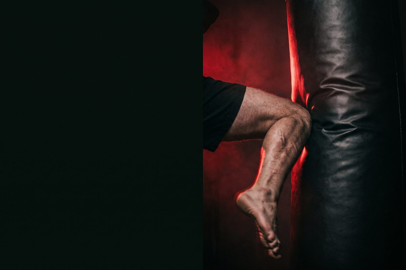 A kickboxer driving a knee into a heavy bag