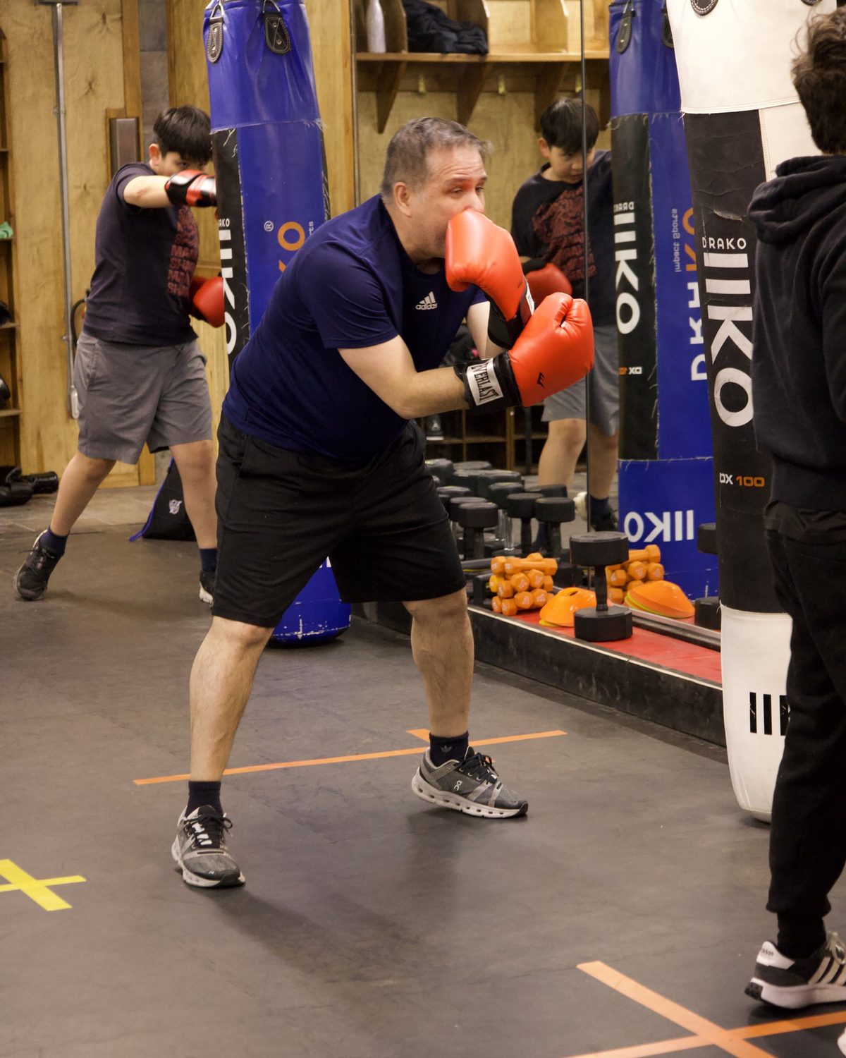 Adults working the heavy bags during an evening class at Kingdom Athletics