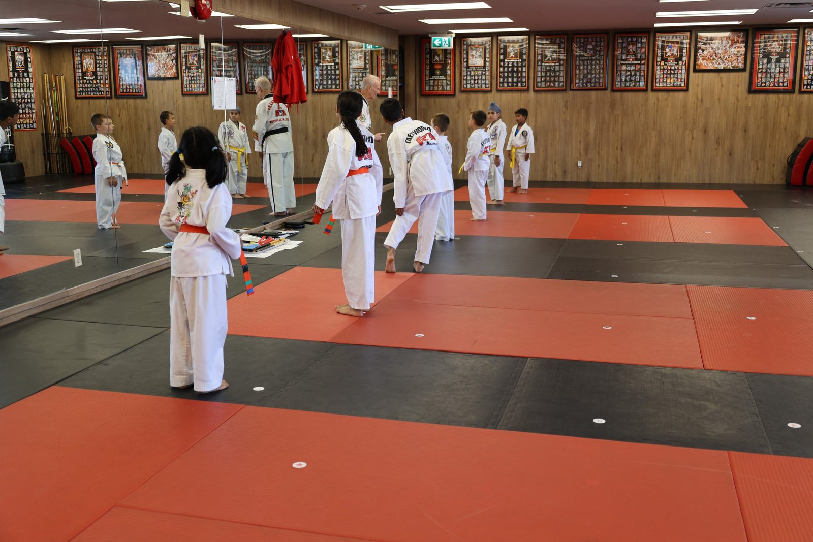 A kids taekwondo class drilling in lines on the mats at Kingdom Athletics